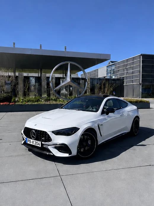 Handyfoto eines weißen Mercedes-Coupés vor einem Firmengebäude bei Tageslicht